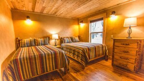 Une chambre avec deux lits, un plancher en bois, une commode et une fenêtre.