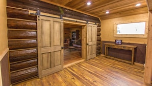 L’intérieur d’une cabane en rondins, avec des murs en bois, une porte coulissante, une cheminée et une fenêtre.