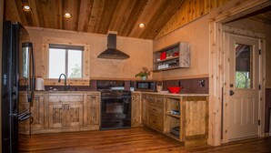 Une cuisine de style rustique, avec des murs en bois, un grand poêle, un four et des armoires en bois.