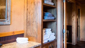Une salle de bain en bois avec une étagère intégrée pour ranger les serviettes, un plan de travail et un miroir.