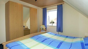 Une chambre avec un grand lit, une armoire en bois et une fenêtre avec des rideaux.