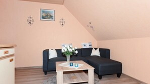 Un salon chaleureux avec un canapé foncé, une table basse en bois et un petit tapis.