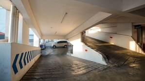 A parking garage with a white car parked near the exit. - Sun Apartment Semarang (Semarang)