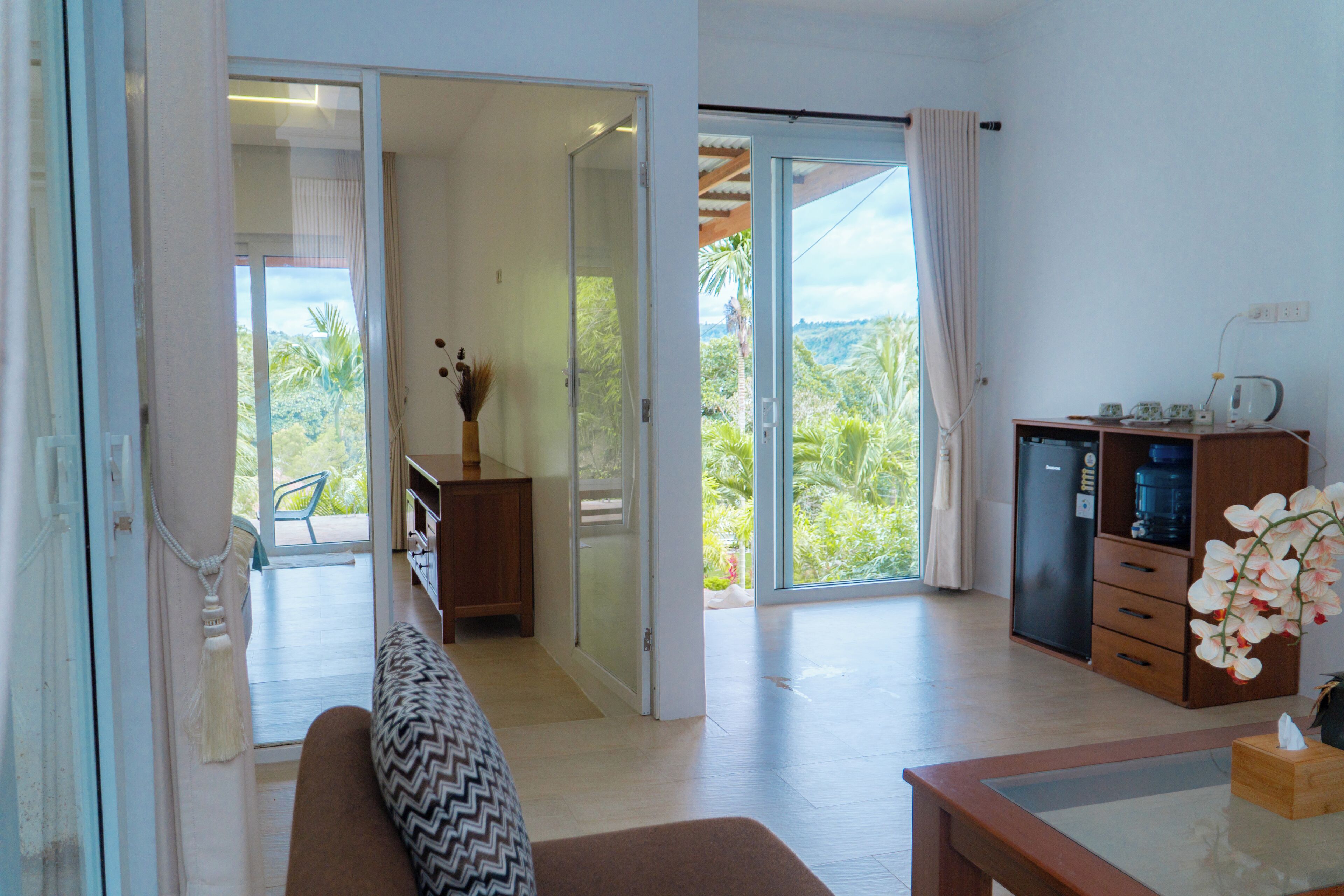A spacious living area with a sliding glass door leading to a balcony, a wooden cabinet, and a small table with a tissue box.