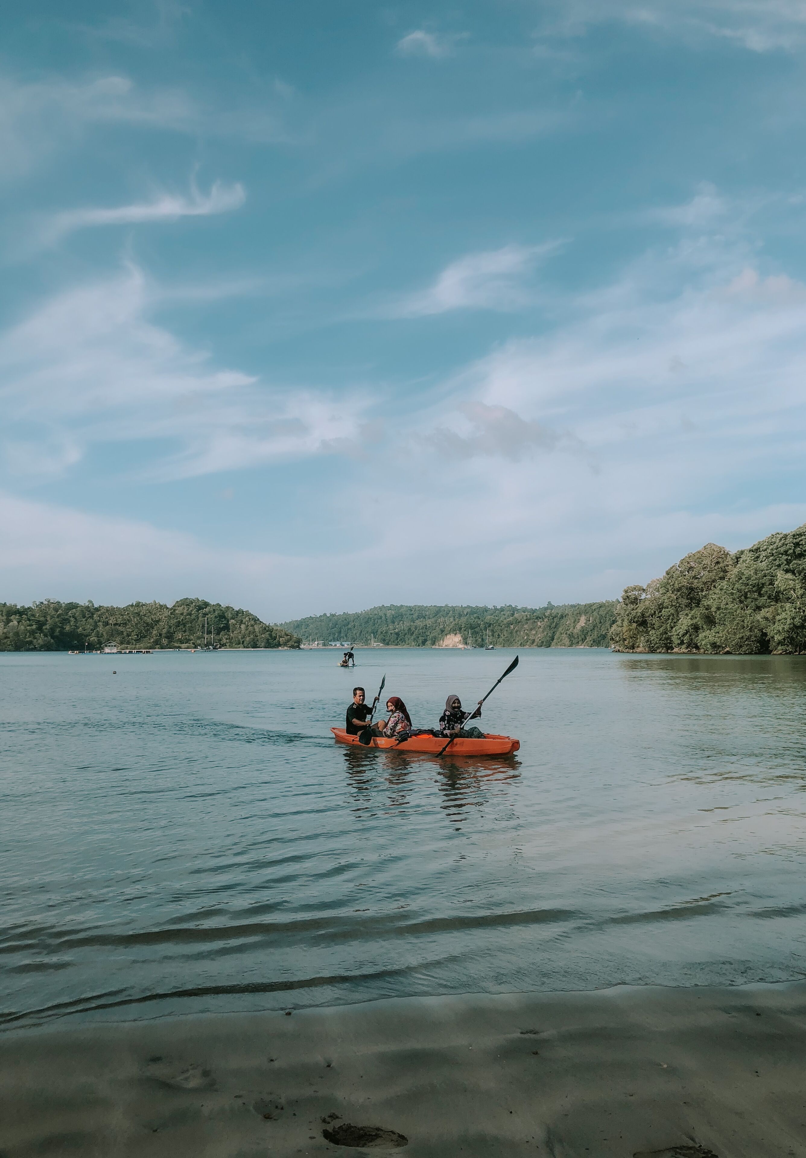 Un lac paisible où l’on peut voir des personnes faire du kayak dans un kayak orange.