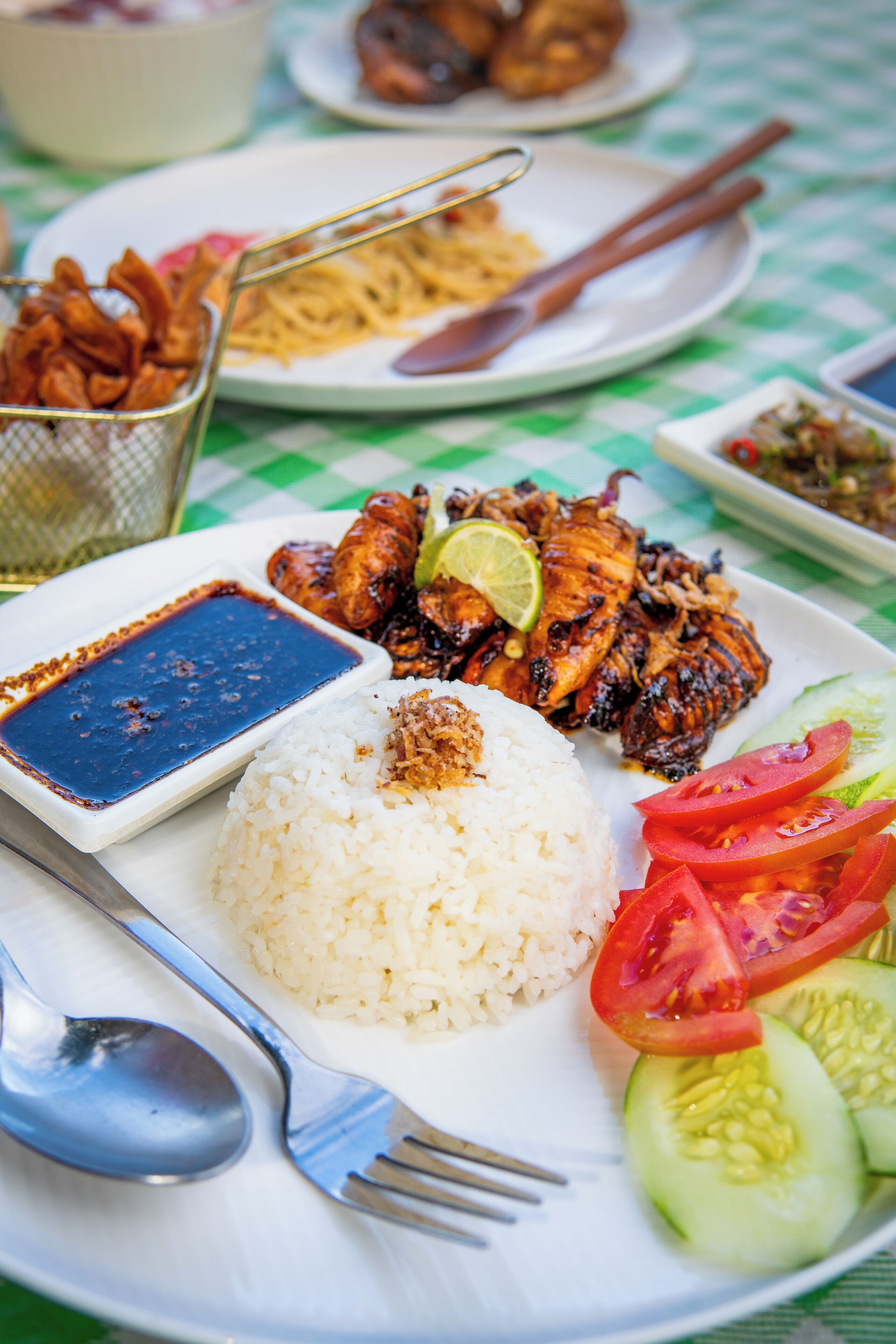 A plate of grilled chicken, rice, and vegetables with a side of sauce.