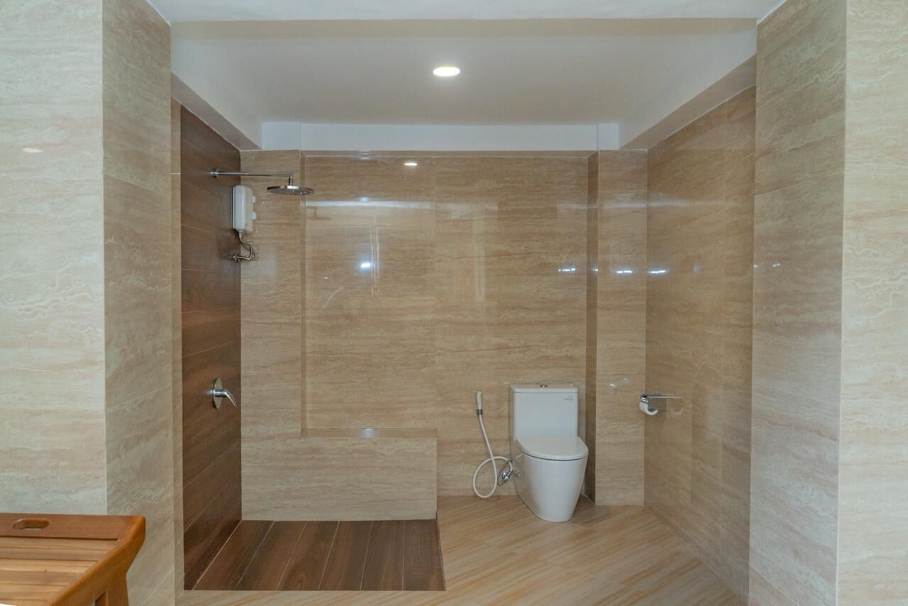 Un bagno moderno con doccia, toilette e uno sgabello in legno.