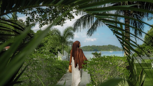 A pathway leading to a body of water, surrounded by lush greenery and palm trees. - The Hawk's Nest Resort (Sabang)