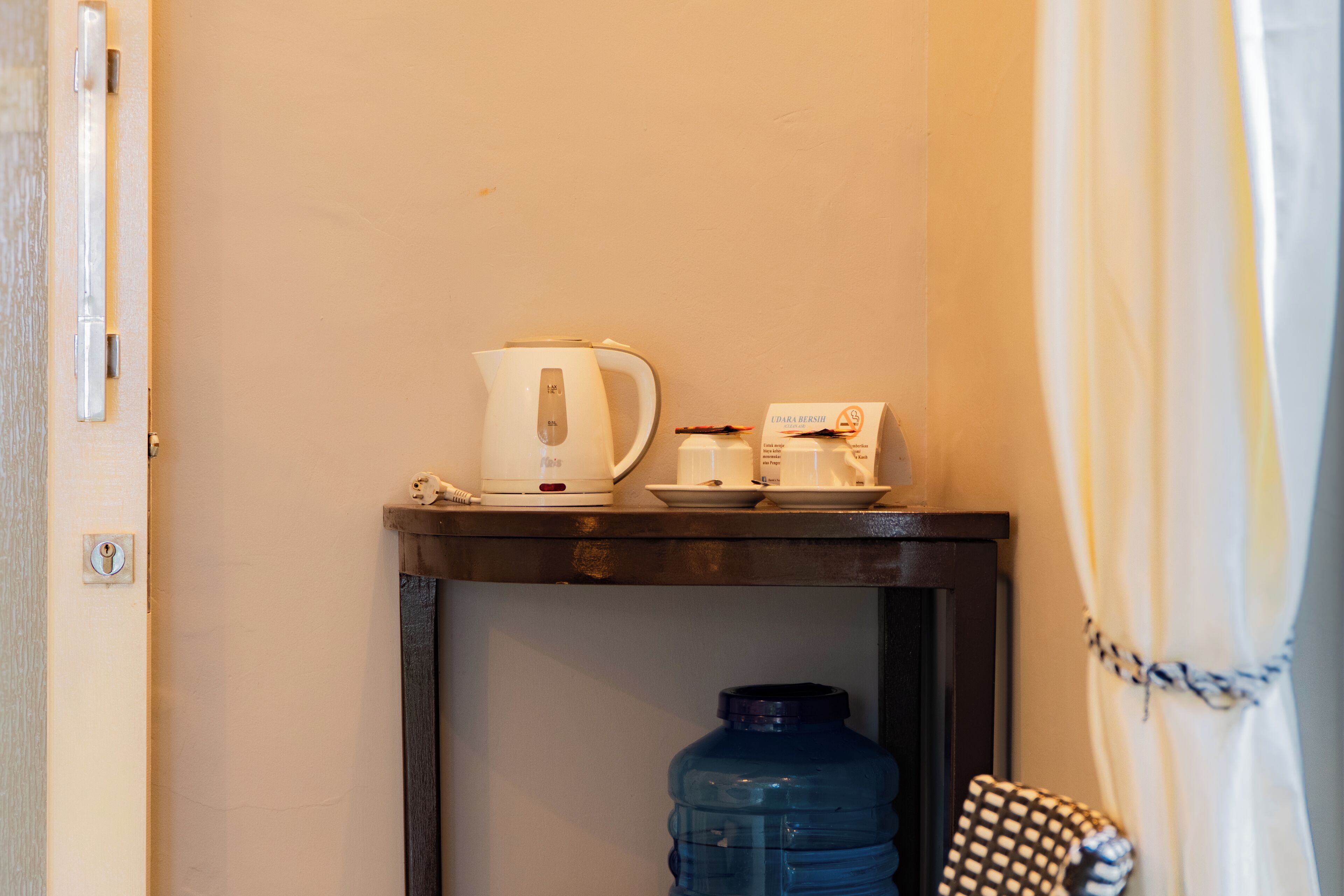 Une petite table avec une machine à café, une boîte et une carafe d’eau dans une chambre d’hôtel.