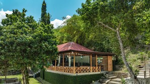 A gazebo-style structure with a red roof, surrounded by lush greenery and stone steps leading up to it. - The Hawk's Nest Resort (Sabang)