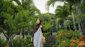 A woman walking on a staircase surrounded by lush greenery and orange flowers. - The Hawk's Nest Resort (Sabang)