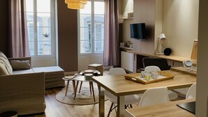 Una sala de estar moderna con un sofá, una mesa de comedor y un televisor montado en la pared.
