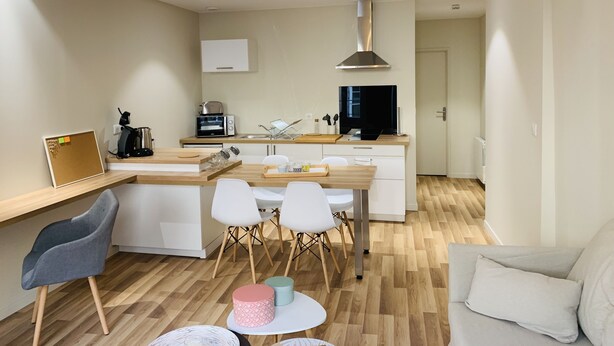 Una cocina moderna con encimera de madera, sillas blancas, una mesa de comedor y un televisor grande.