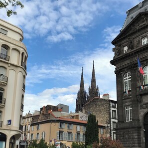 Ein historisches Gebäude mit gotischen Türmen, ein modernes Gebäude mit Graffiti und ein traditionelles Gebäude mit Fensterläden.