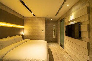 A modern hotel room with a large bed, a flat-screen TV mounted on the wall, and a walk-in closet. - Hotel Bell (Taichung)