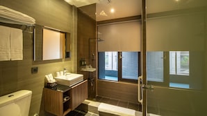 Un baño moderno con ducha de vidrio, tocador con lavamanos y inodoro.