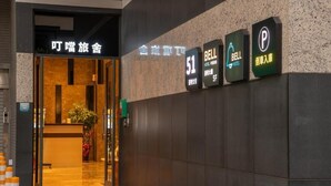 Entrada de hotel con mostrador de recepción, cartel de Bell Hotel y señal de estacionamiento.