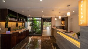 Un área de recepción moderna con piso de mármol, mostrador de madera y un letrero que dice 'HELLO'.