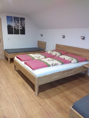 Une chambre avec deux lits en bois, l’un recouvert d’une couette à carreaux rouges et blancs, et l’autre d’une couette de couleur foncée.