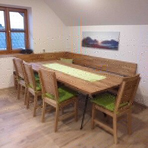 A dining area with a long wooden table and chairs, a window, and a framed picture on the wall. - Minabauer - Apartment 1 (Altmünster am Traunsee)