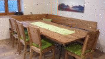 A dining area with a long table and chairs, a window, and a wall-mounted picture.