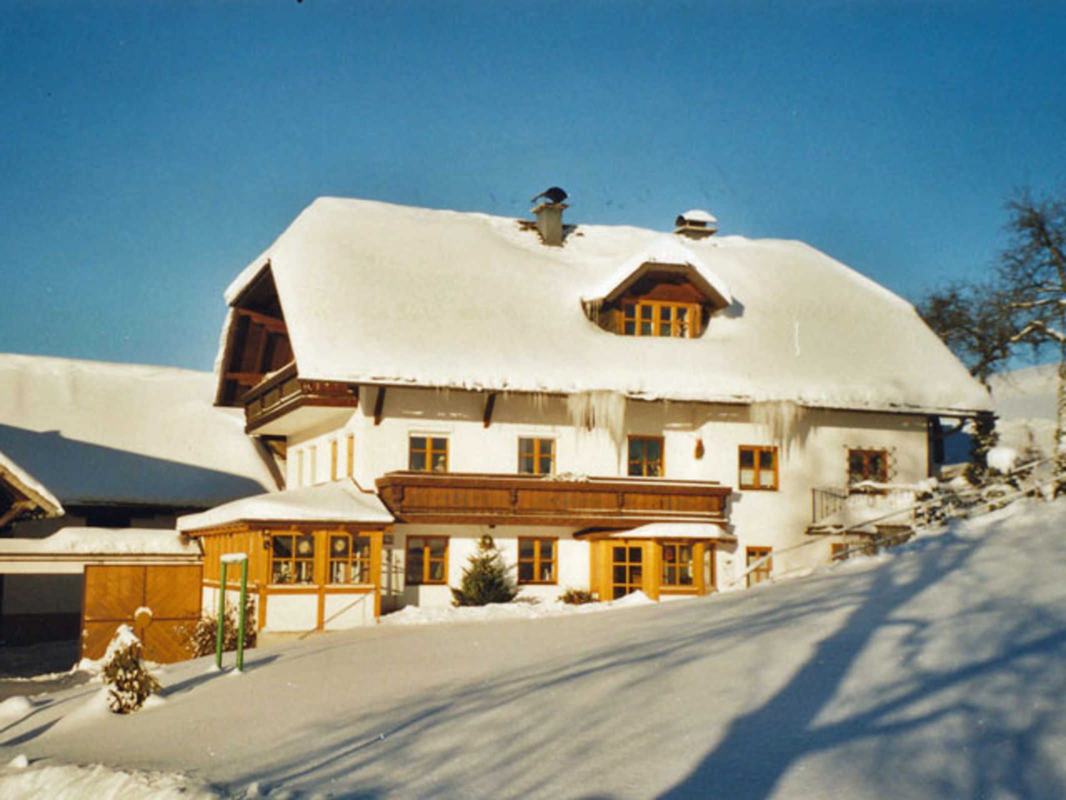 A snow-covered building with a sloped roof, wooden exterior, and multiple windows.