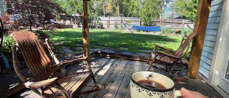 Una terraza de madera con dos mecedoras y una taza de café.
