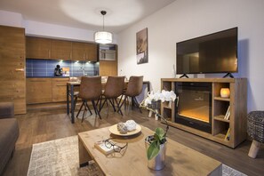 A modern living room with a wooden coffee table, a TV, and a fireplace. - Apartment in ski Village les Saisies (Hauteluce)