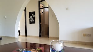 A magazine on a table with a glass vase containing marbles. - Alis Plaza (Diani Beach)