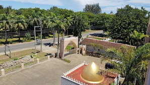 A courtyard with a golden dome structure, a stone bridge, and lush greenery. - Alis Plaza (Diani Beach)