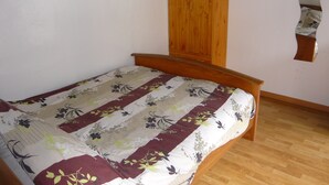 Un dormitorio con estructura de cama de madera, colcha estampada y armario de madera.