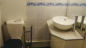 Un baño pequeño con inodoro, lavamanos y espejo.