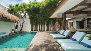 A pool area with lounge chairs and a wooden deck. - Villa Metisse by Villa Finder (Seminyak)