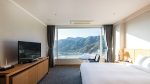 A hotel room with a large bed, a TV on a wooden desk, a small table, and a view of mountains through the window. - Take Hotel & Resort Inje Speedium (Inje)