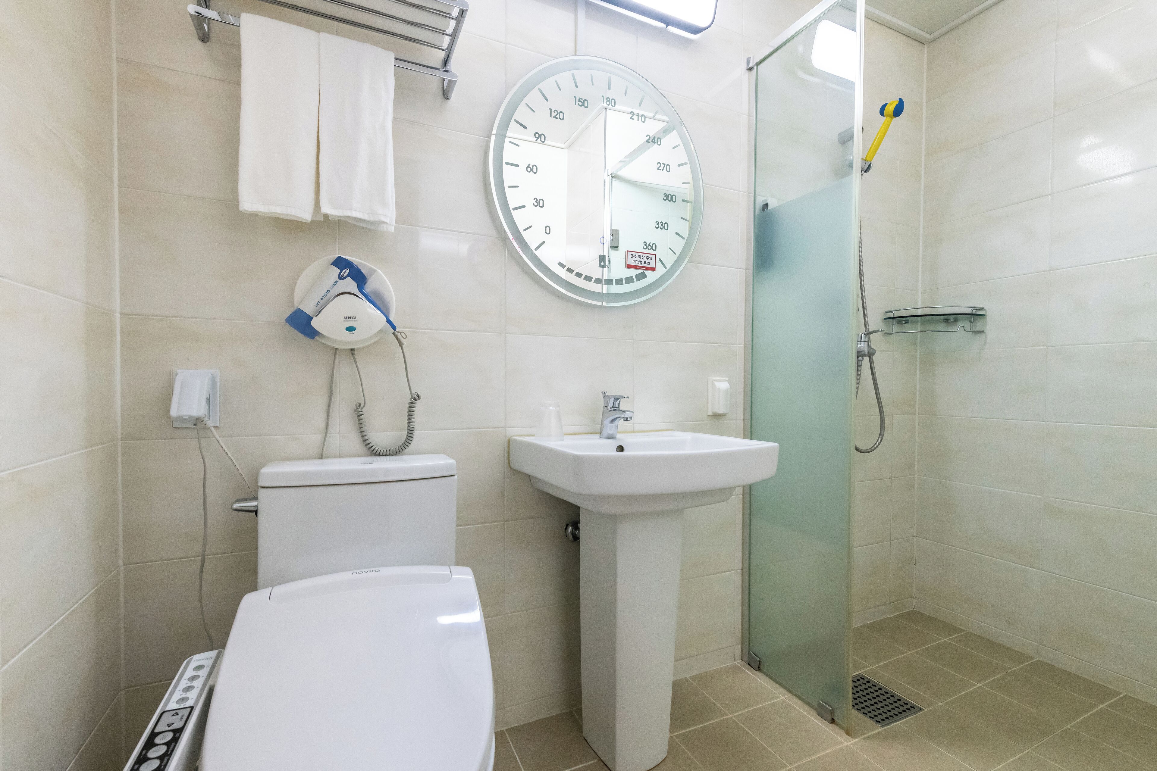 A bathroom with a toilet, sink, and glass shower enclosure.