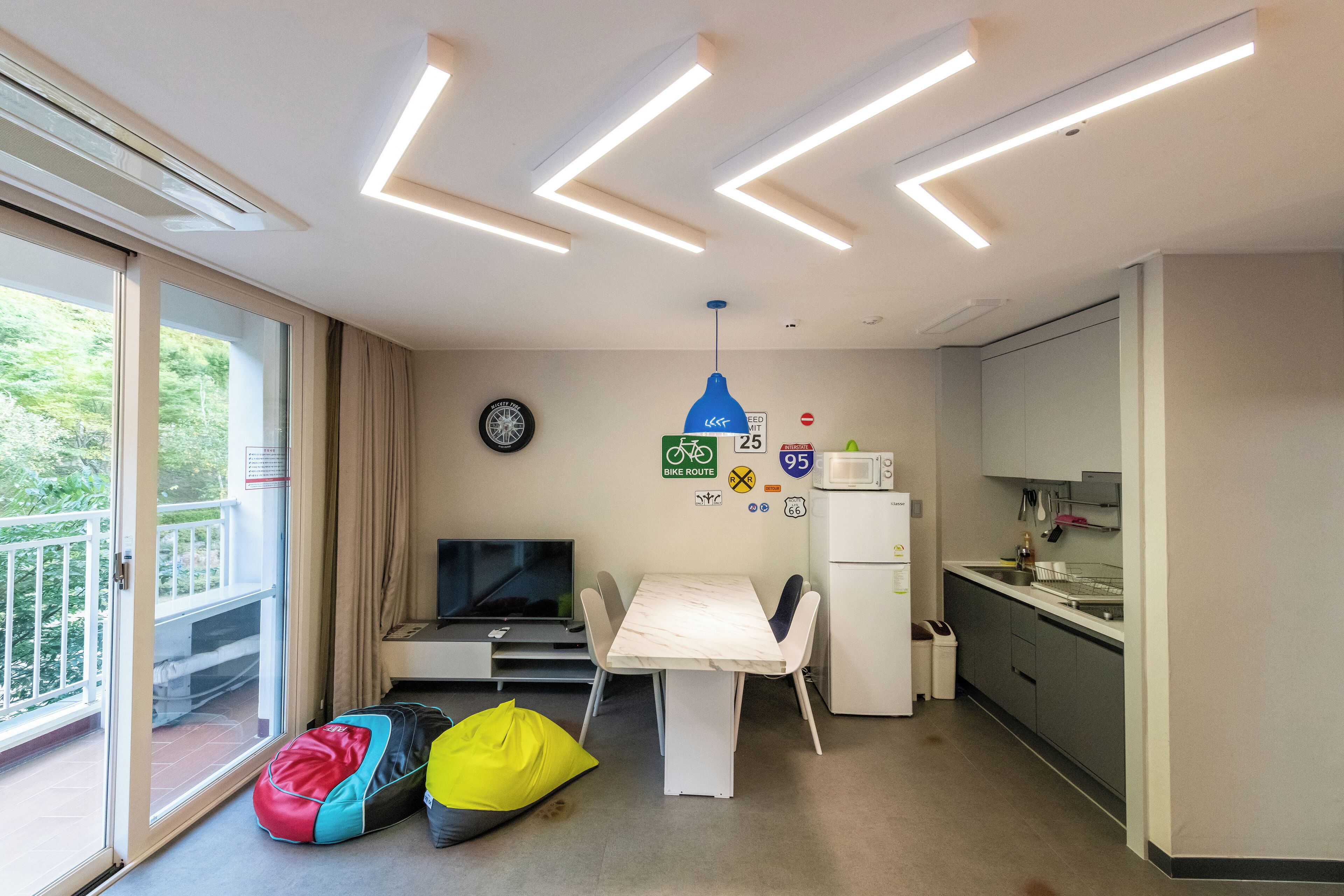 A compact room with a dining table, a TV, and a kitchenette.