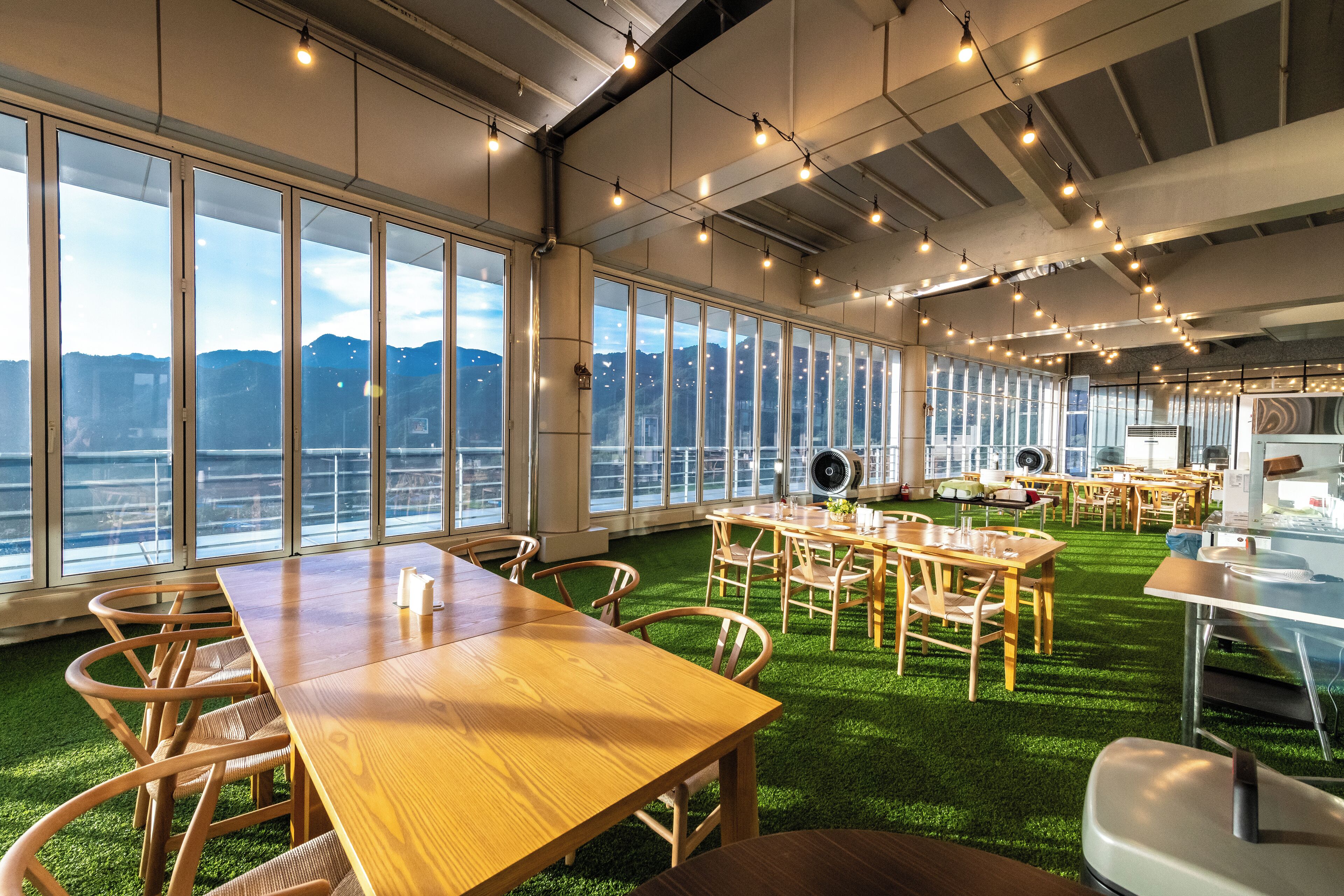 A spacious room with large windows, a wooden table, and chairs.