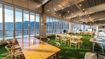 A spacious room with large windows, a wooden table, and chairs.