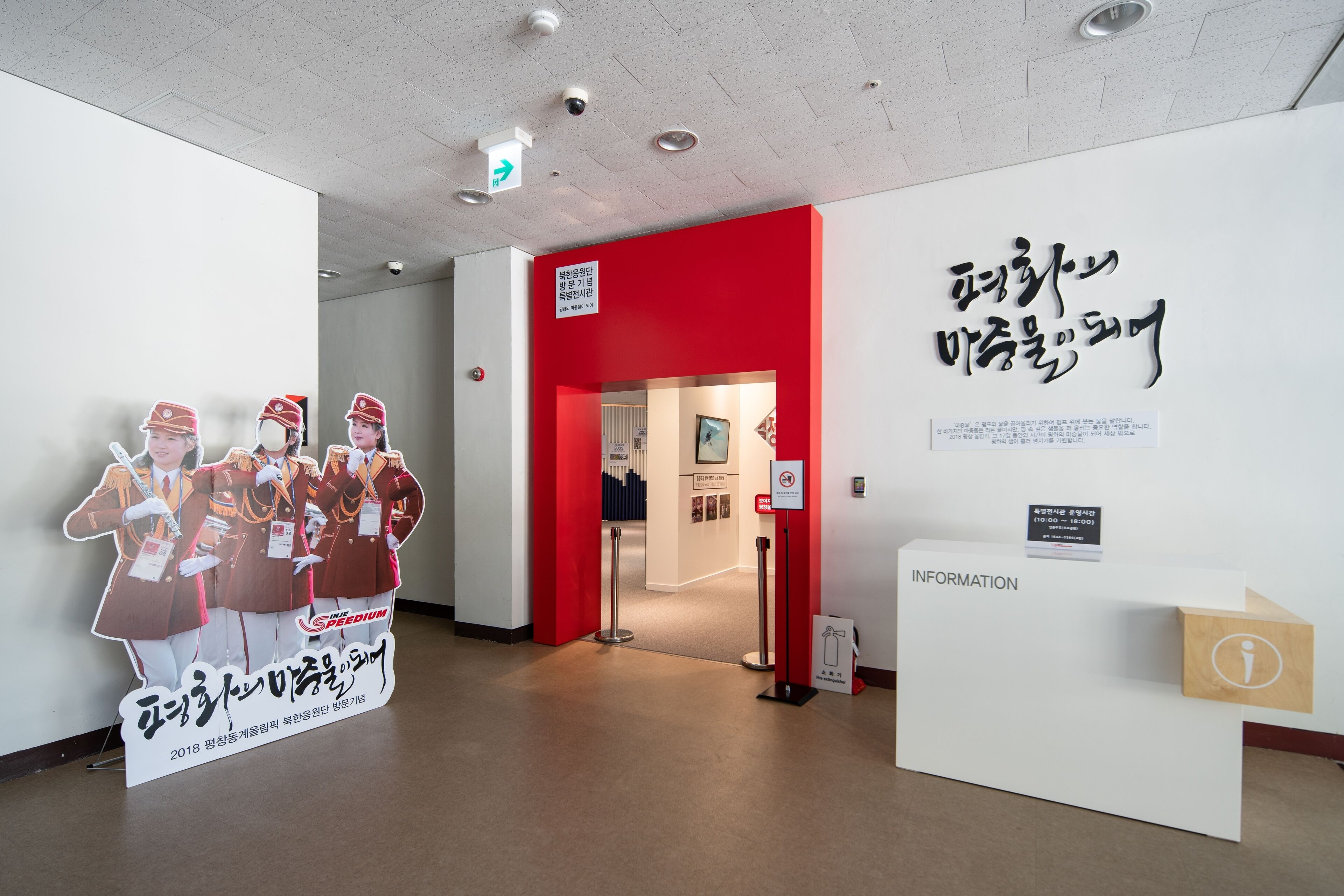 An indoor space with a red accent wall, informational signage, and a display featuring figures in uniform.