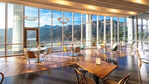 A spacious dining area with large windows offering mountain views, modern furniture, and pendant lighting. - Take Hotel & Resort Inje Speedium (Inje)