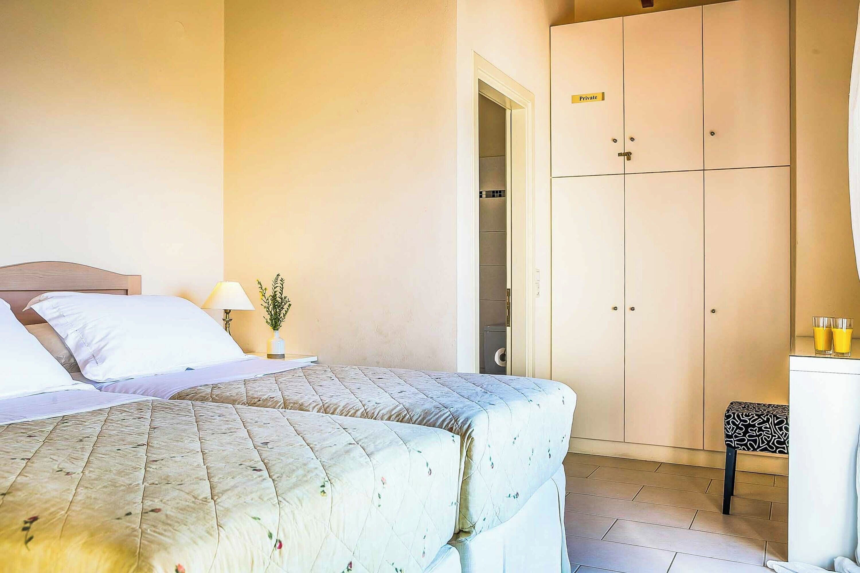 A hotel room with two beds, a desk, and a wardrobe.