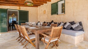 A wooden dining table set with chairs, a sofa with cushions, and a hanging light fixture. - Fantastic Villa with Pool, Wi-Fi, Terrace, Garden and Sea View (Sant Josep de sa Talaia)