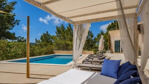 A poolside area with a covered seating area, a pool, and a view of trees and mountains. - Fantastic Villa with Pool, Wi-Fi, Terrace, Garden and Sea View (Sant Josep de sa Talaia)