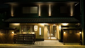 Un hôtel japonais traditionnel, avec une façade en bois, des portes coulissantes et une enseigne indiquant qu’il se trouve à Kyoto.