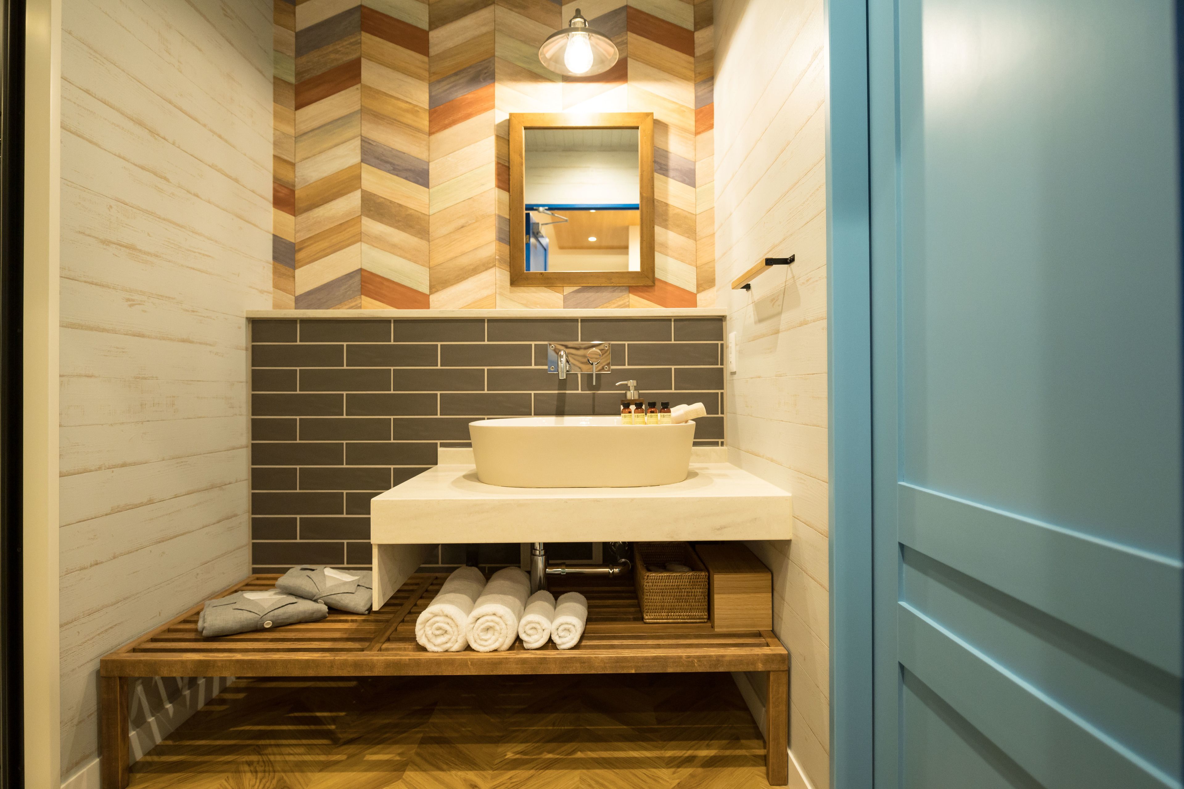 A bathroom with a wooden bench, a sink, and a mirror.