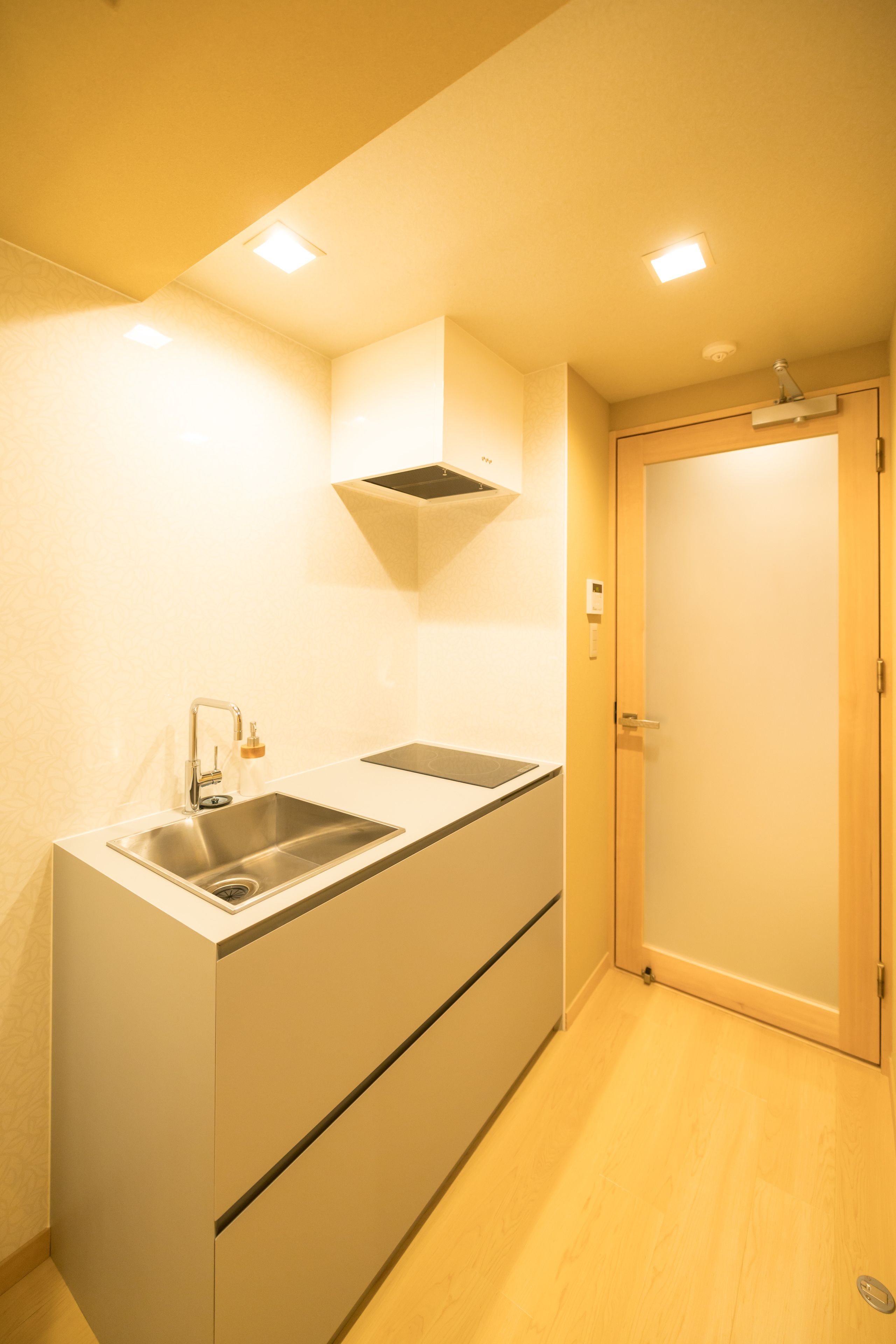 A compact kitchen with a sink, countertop, and a wooden door.