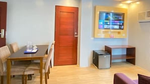 Una sala de estar moderna con una mesa de comedor de madera, una puerta roja, un televisor de pantalla plana montado en la pared y un mueble pequeño.
