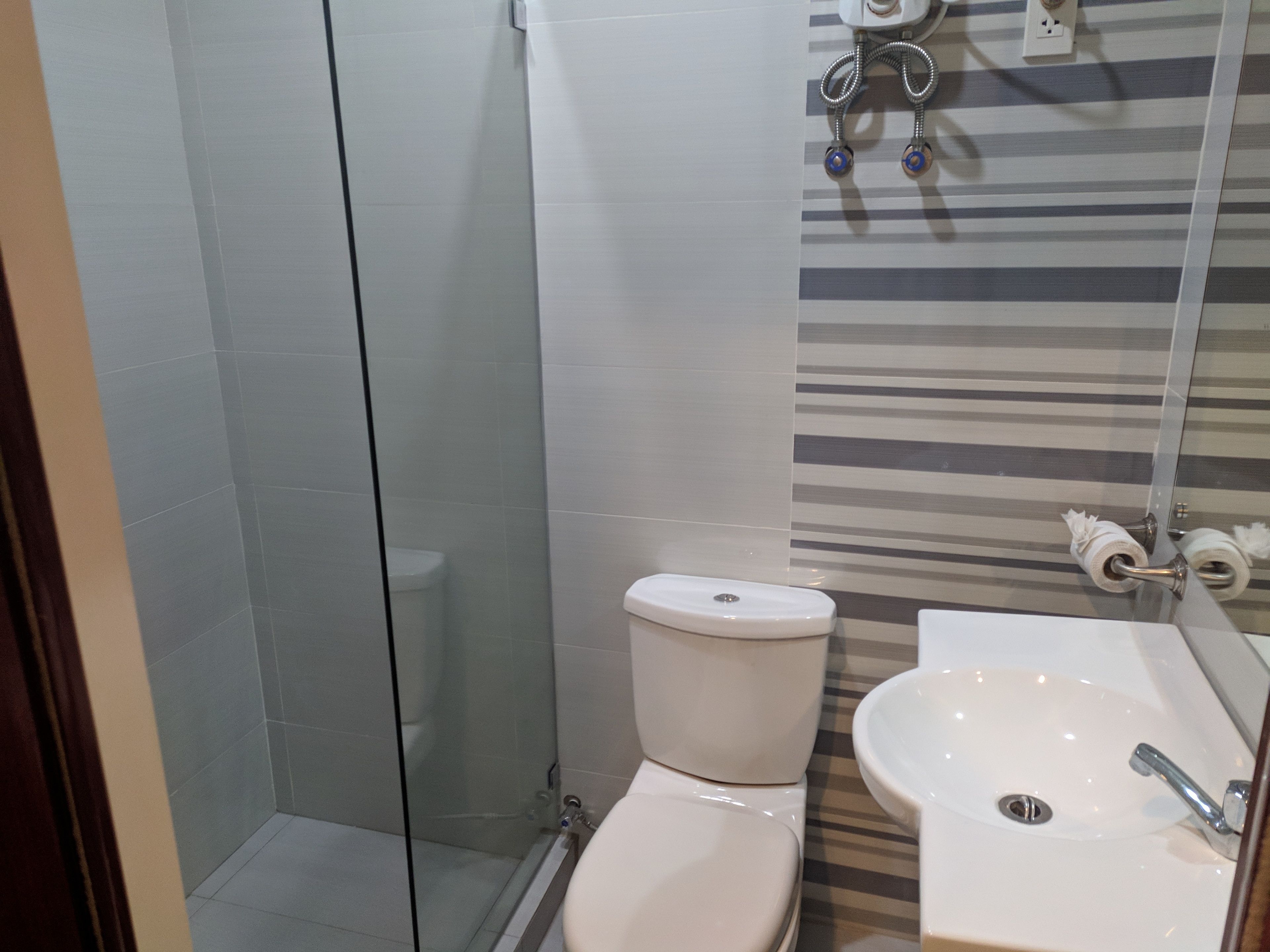 A bathroom with a glass shower enclosure, a white toilet, and a white sink with a chrome faucet.