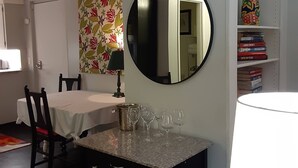Un coin repas comprenant une table, des chaises, un lustre, un miroir et une bibliothèque remplie de livres.