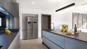 A modern kitchen with a stainless steel refrigerator, a built-in oven, and a large island with a sink.